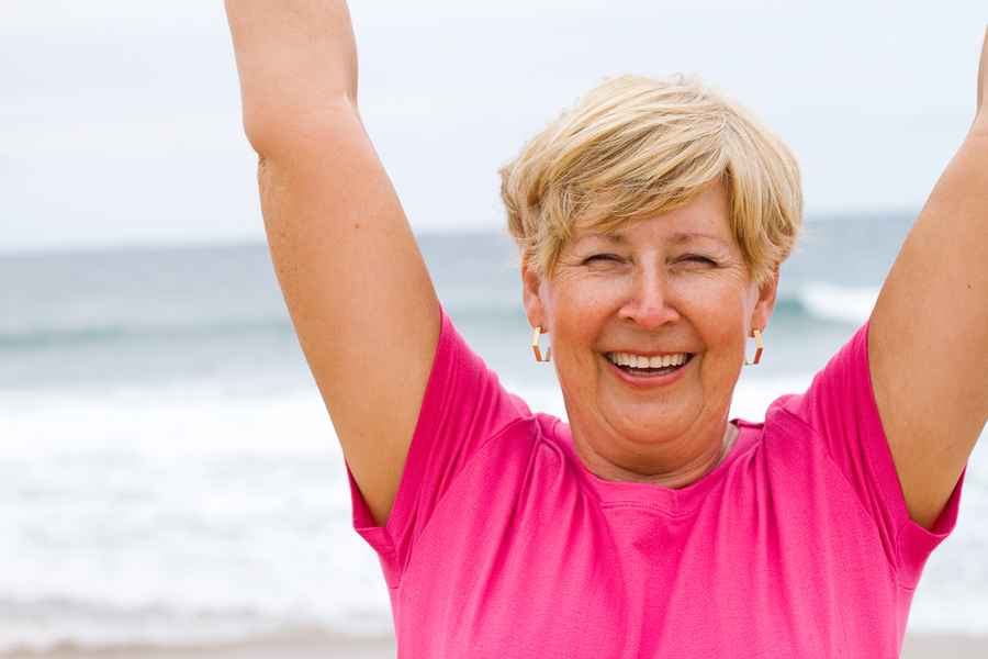 happy elderly woman doing exercise on beach